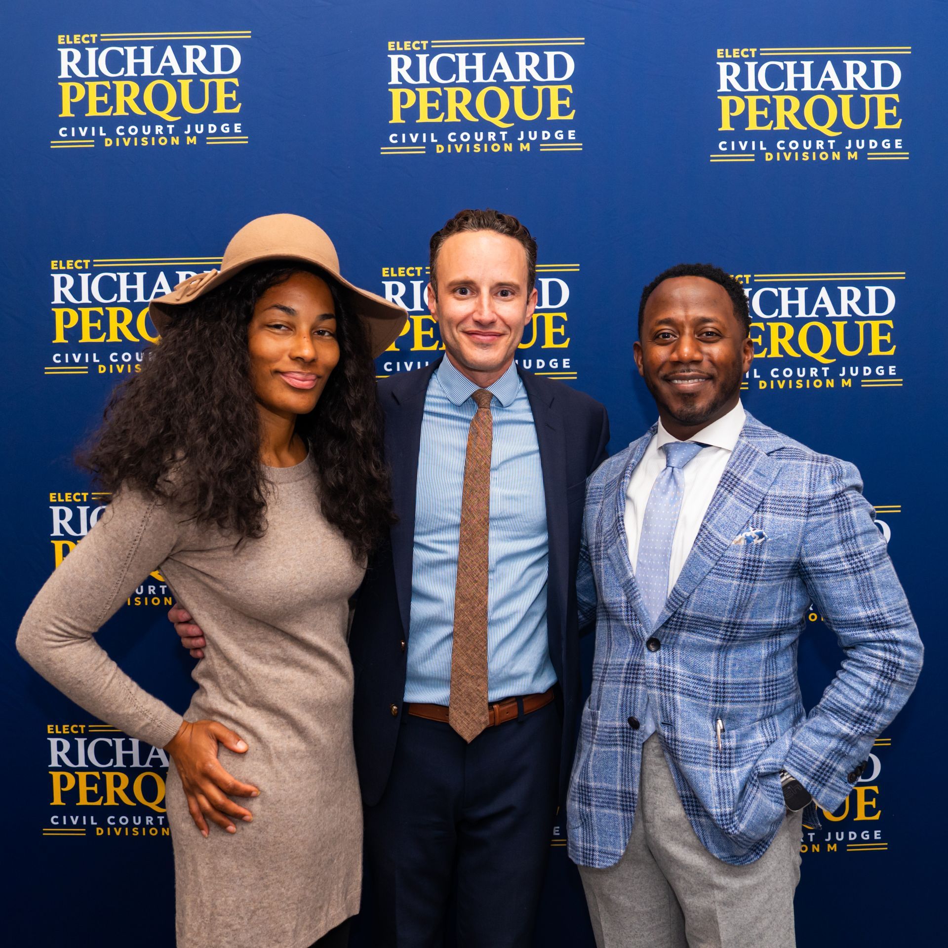 Three people posing in front of a backdrop that says 