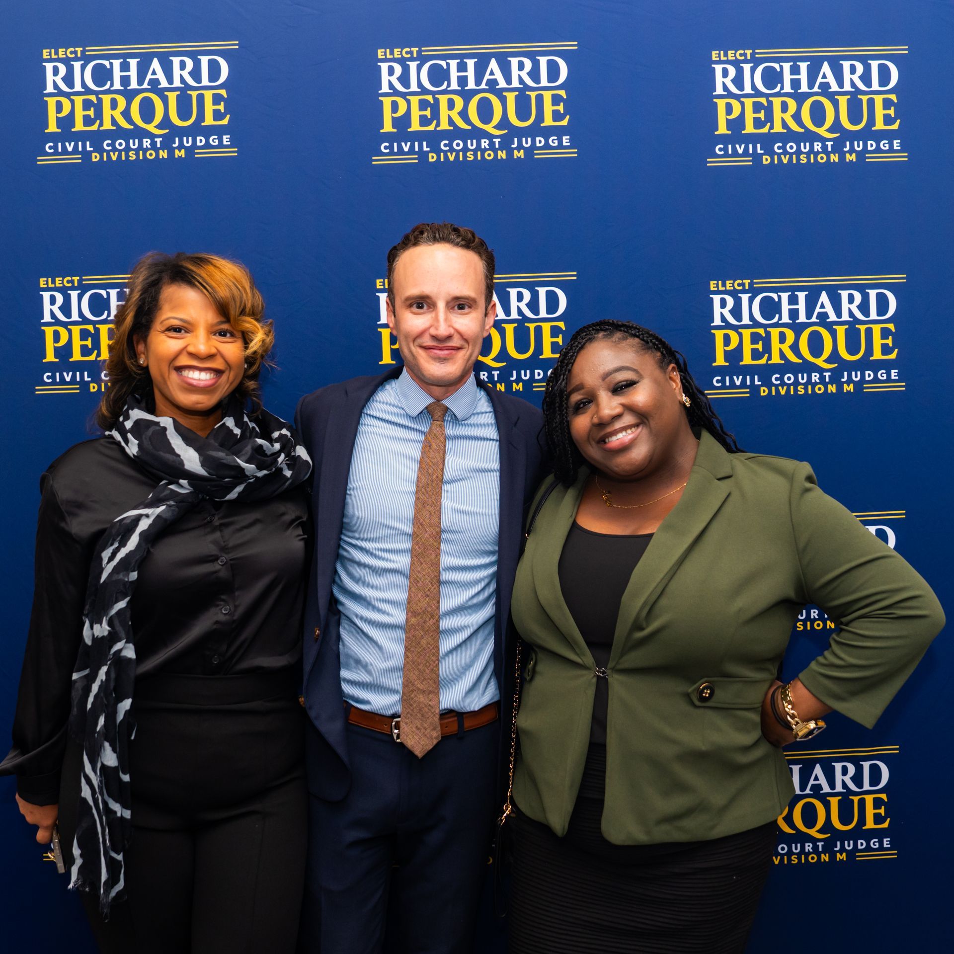 Three people smiling in front of a banner for Richard Perque, a civil court judge candidate.