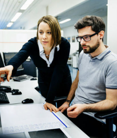 Woman pointing at a computer screen, explaining something to a man with glasses. Woman pointing at a computer screen, explaining something to a man with glasses.
