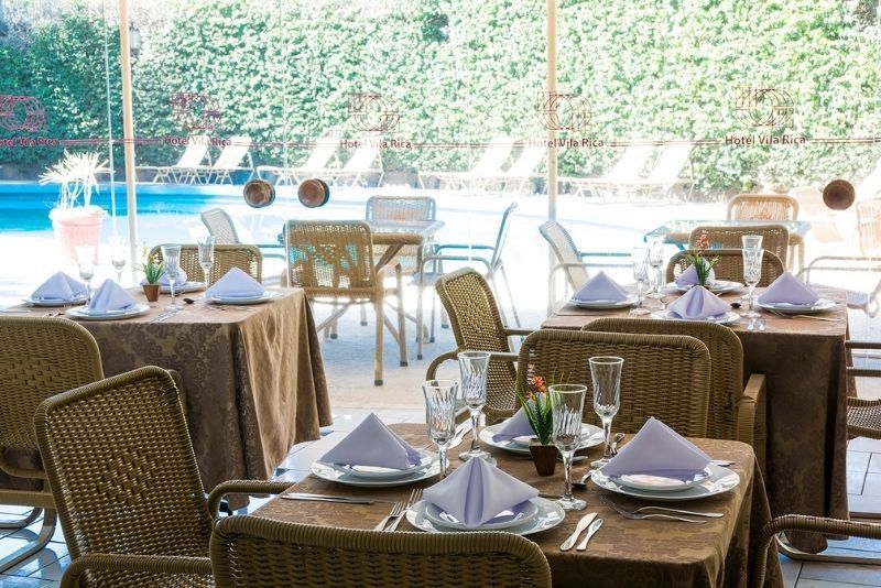 Um restaurante com mesas e cadeiras e uma piscina ao fundo