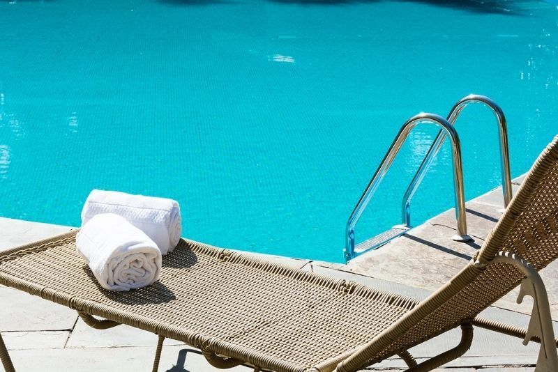 Duas toalhas estão em uma espreguiçadeira ao lado de uma piscina.