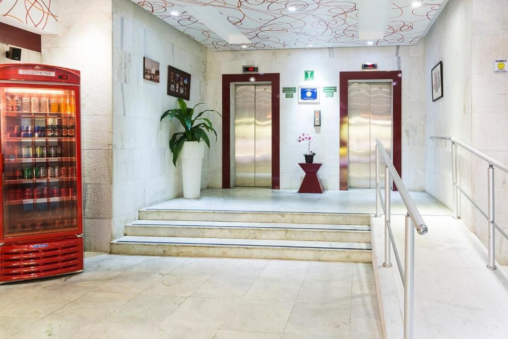 Um corredor com dois elevadores e uma geladeira vermelha
