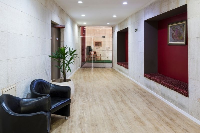 Há duas cadeiras e uma planta no corredor.