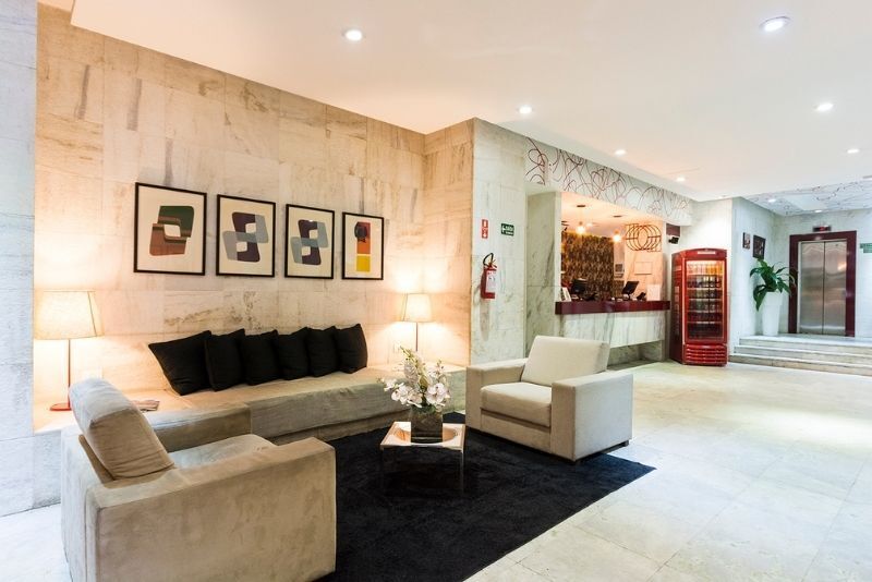 Uma sala de estar com um sofá, cadeiras e uma mesa no saguão de um hotel.