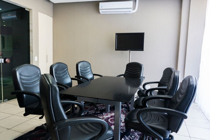 Uma sala de conferências com mesa, cadeiras e uma TV de tela plana.