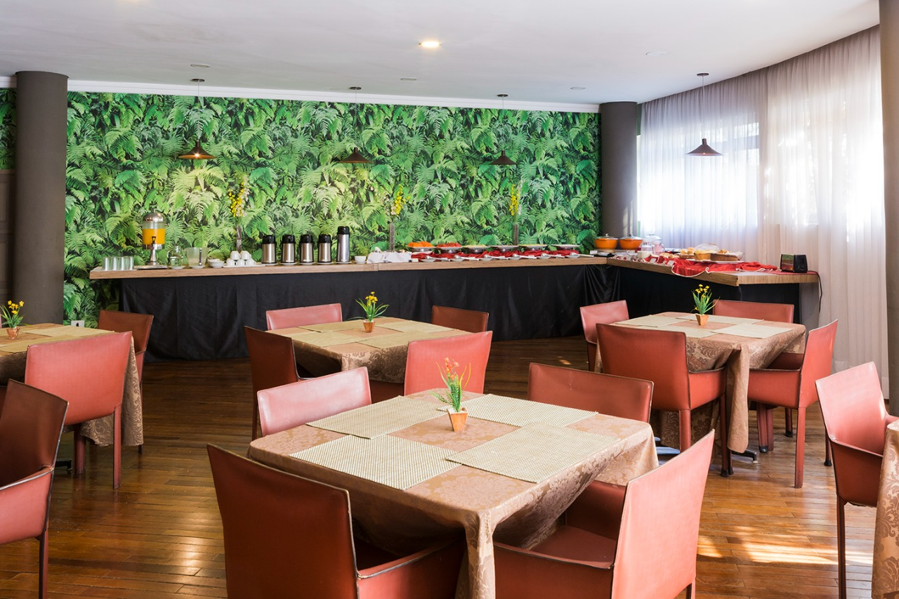 Um restaurante com mesas e cadeiras e um buffet.