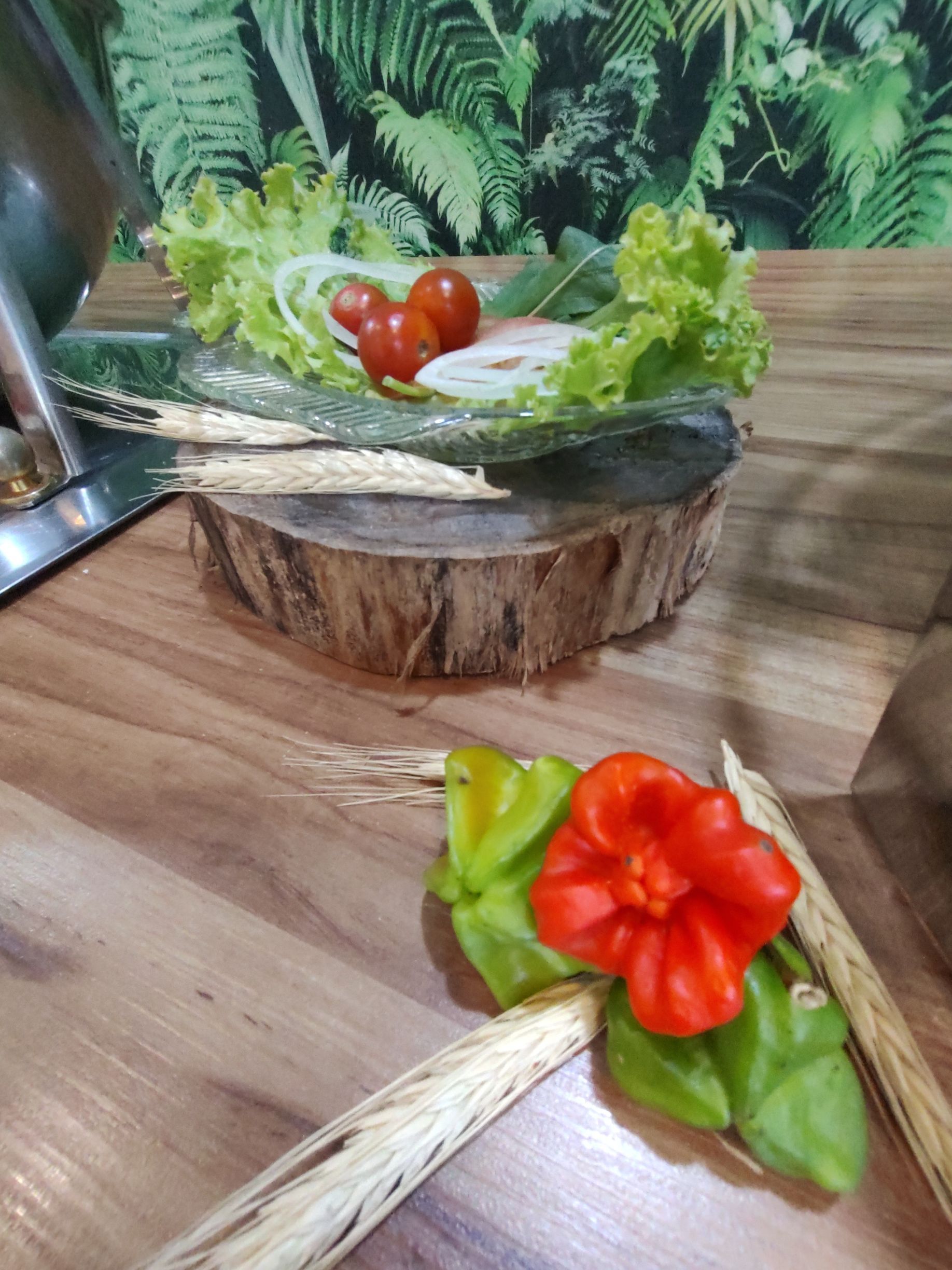 Uma mesa de madeira coberta com uma tigela de vegetais e uma flor.