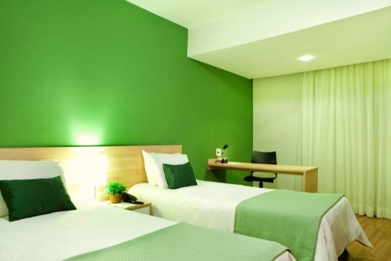 Um quarto de hotel com duas camas e paredes verdes