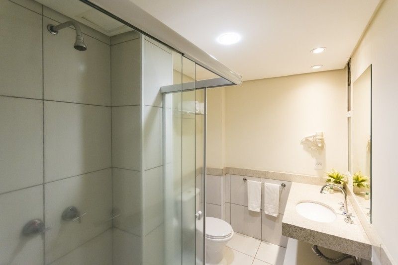 Um banheiro com vaso sanitário, pia, chuveiro e espelho.