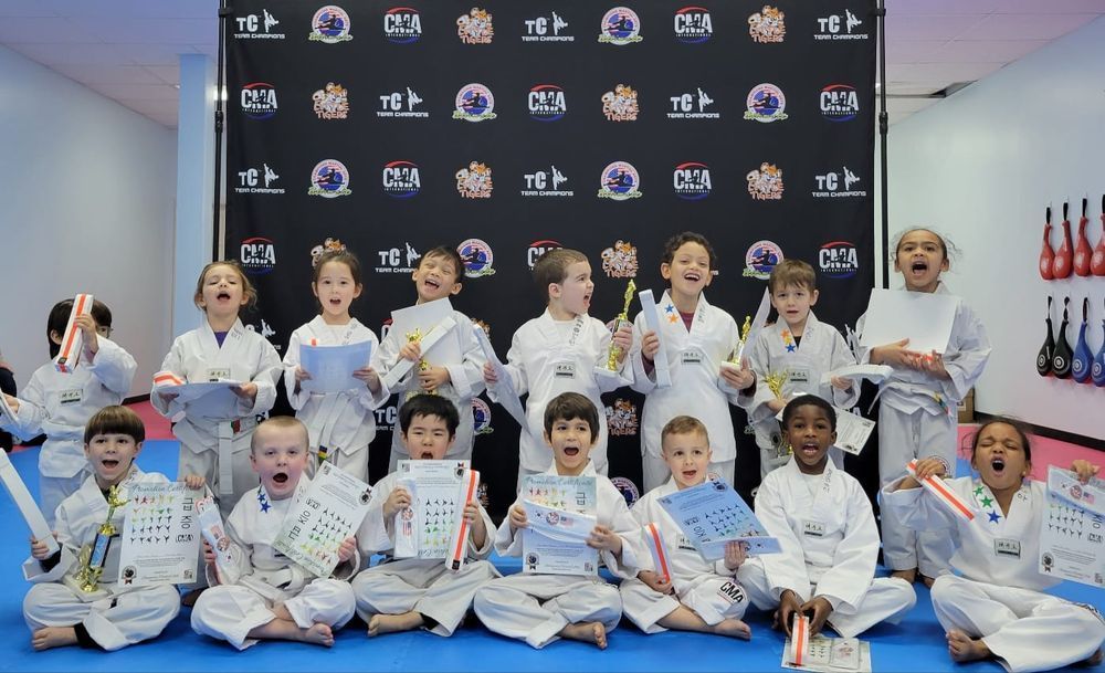 A group of children in karate uniforms are posing for a picture.