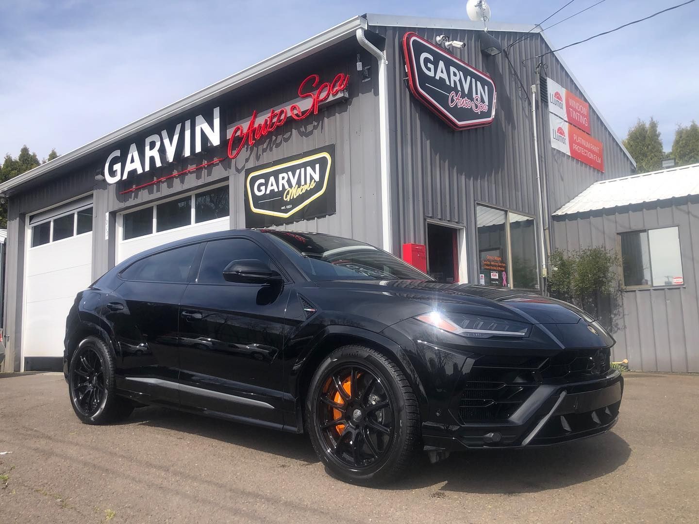 Black sports car parked outside Garvin Customs auto shop.