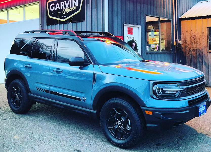 Blue SUV parked outside a GARVIN dealership building with a black roof and wheels