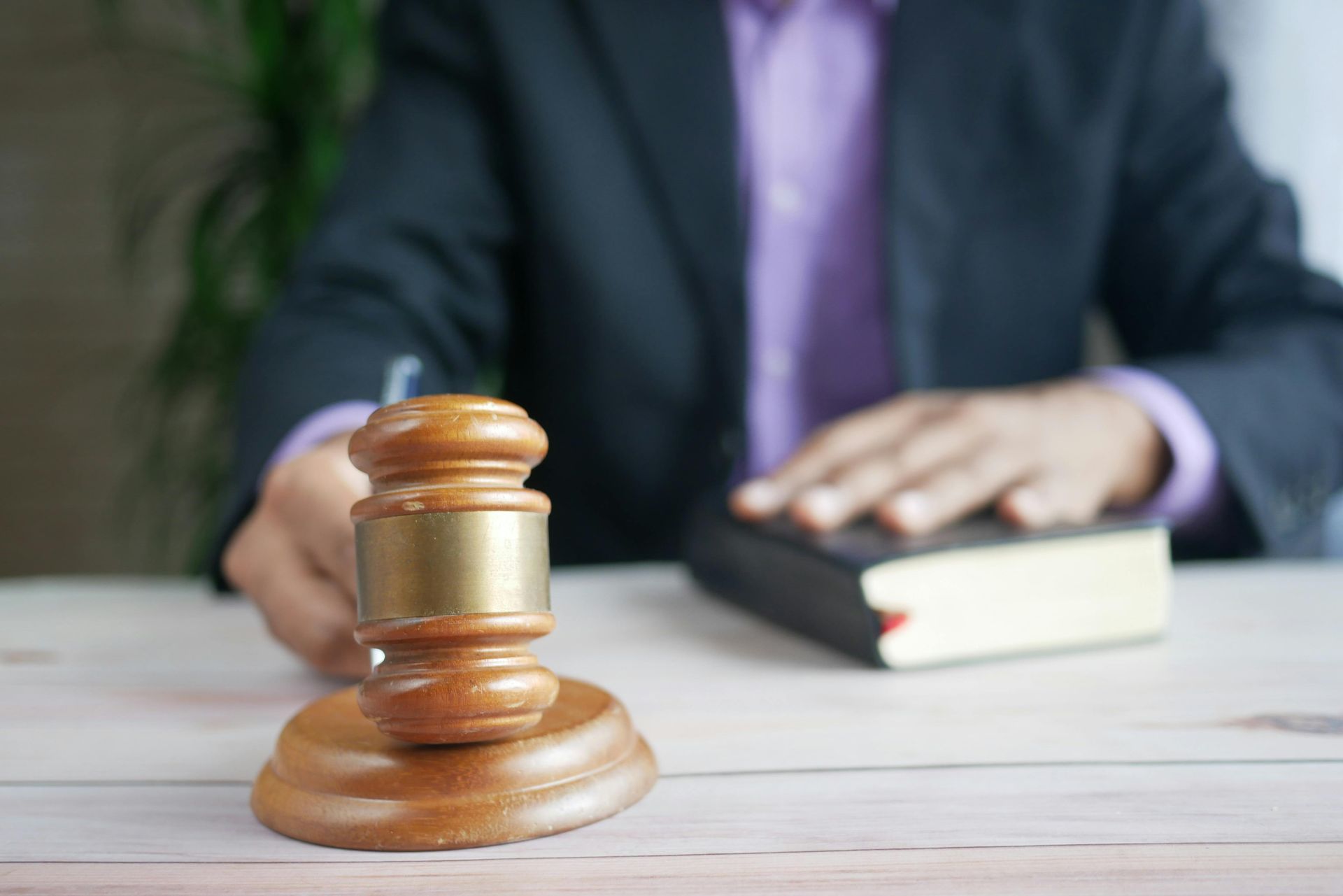 A judge is sitting at a table with a book and a wooden gavel.