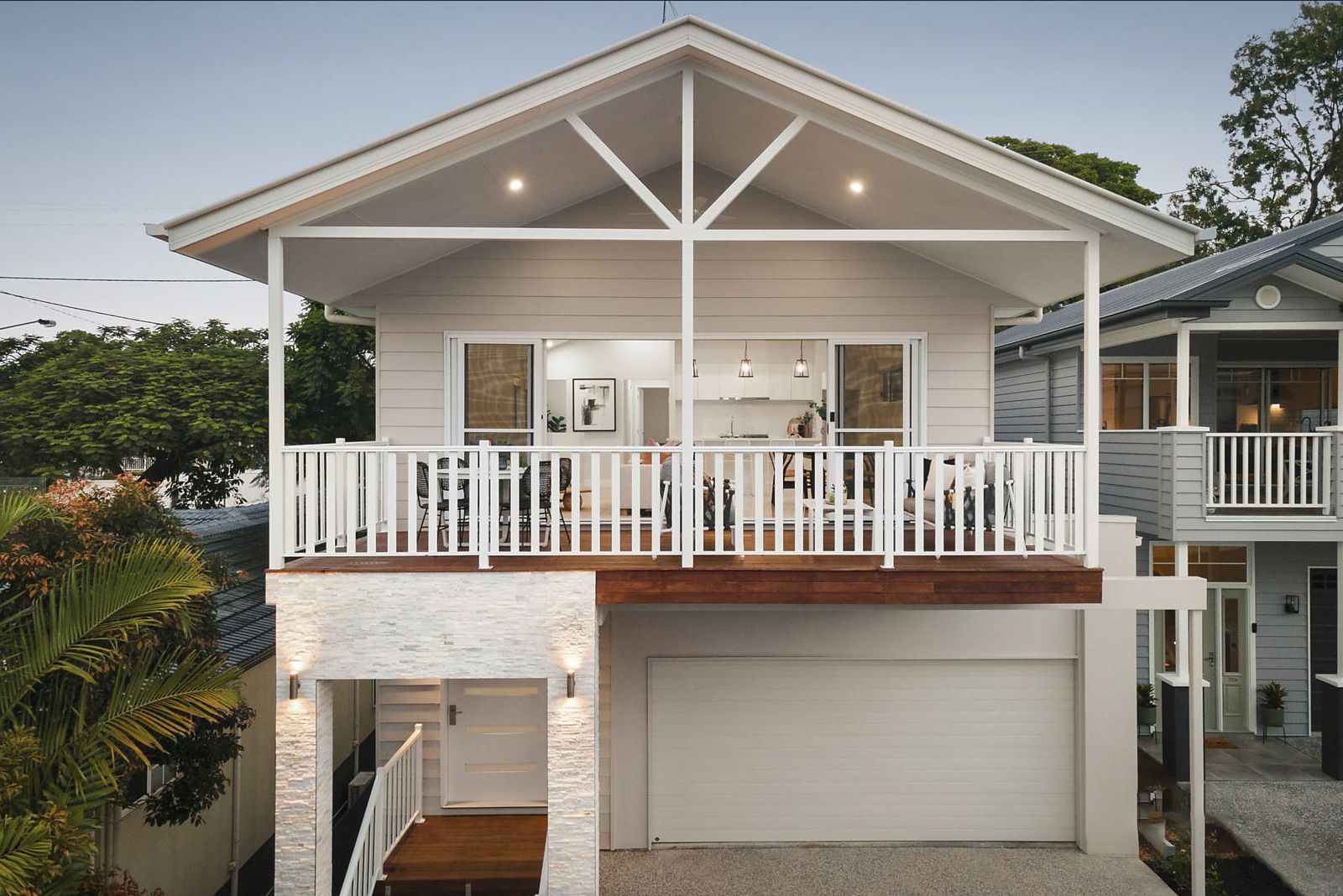 A two-story house with a white exterior and a balcony, featuring a garage on the ground floor.
