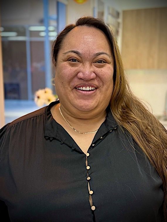 Woman with brown hair and black shirt smiling in an office setting. Jade Taka