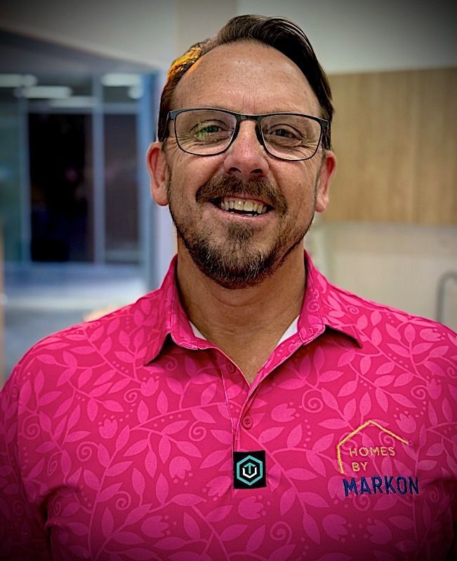 Man with glasses smiles, wearing a pink floral polo shirt,  Mark Uzzell