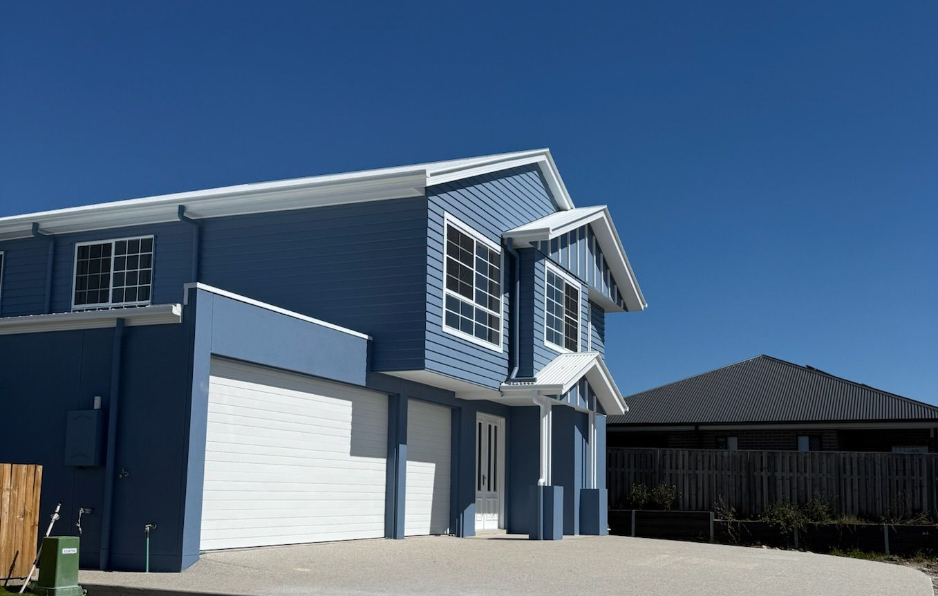 Man in sunglasses stands with arms raised in a bright, open-concept home with a staircase.