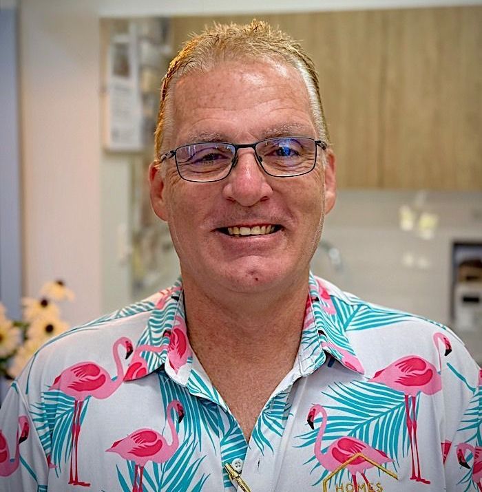 Man with glasses smiles, wearing a pink flamingo shirt. Rob Quinn