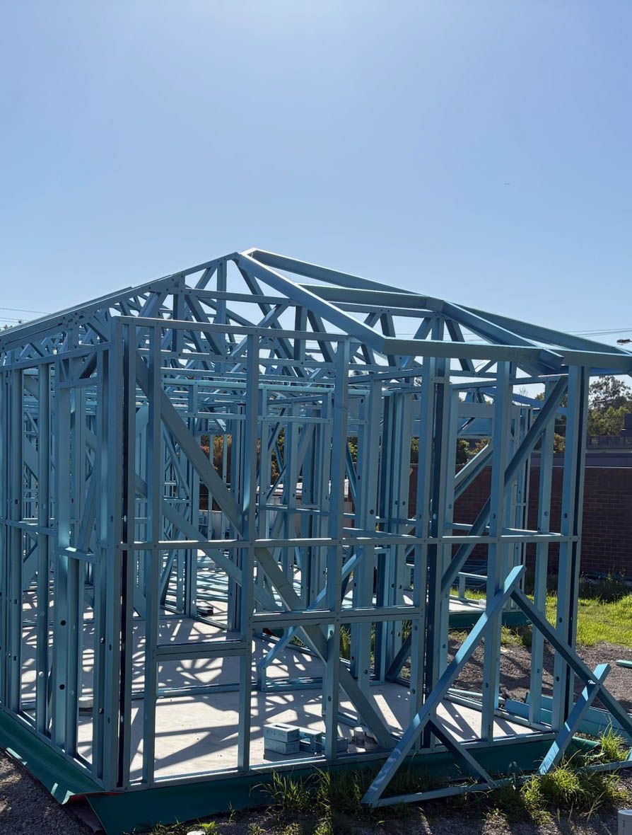 Blue TRUECORE® Steel frame of a small building under construction, set against a bright blue sky.