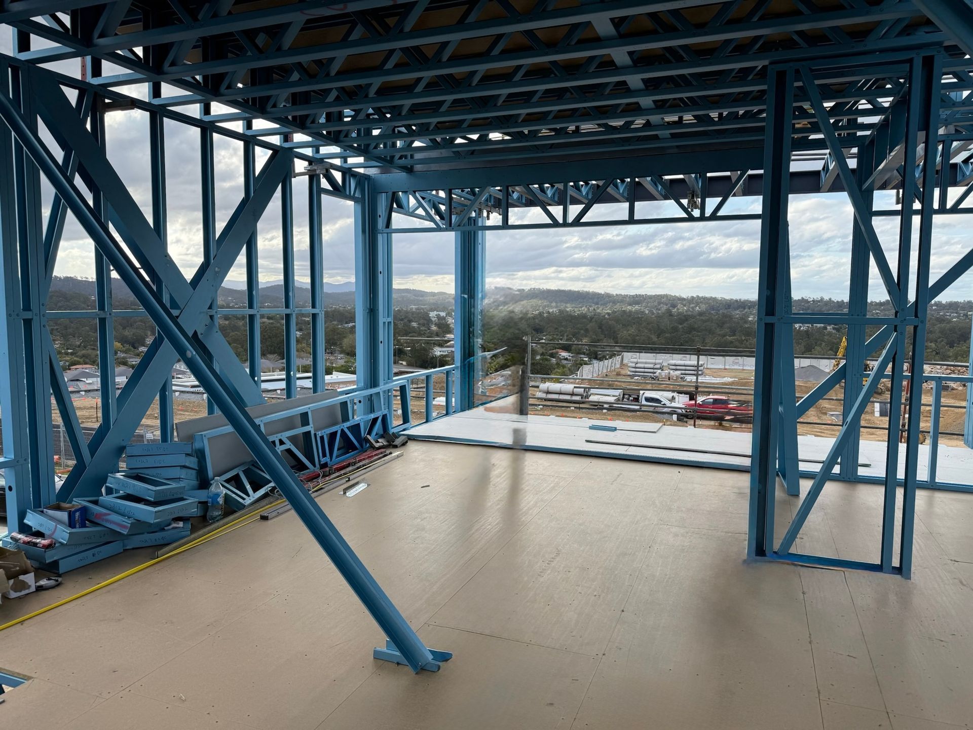 Interior view of a building under construction, steel frame with a scenic view through the open wall.