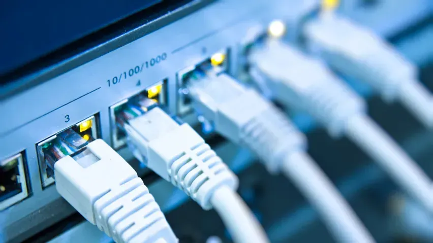 Close-up of an Ethernet switch with white cables plugged into ports, indicating network connectivity.