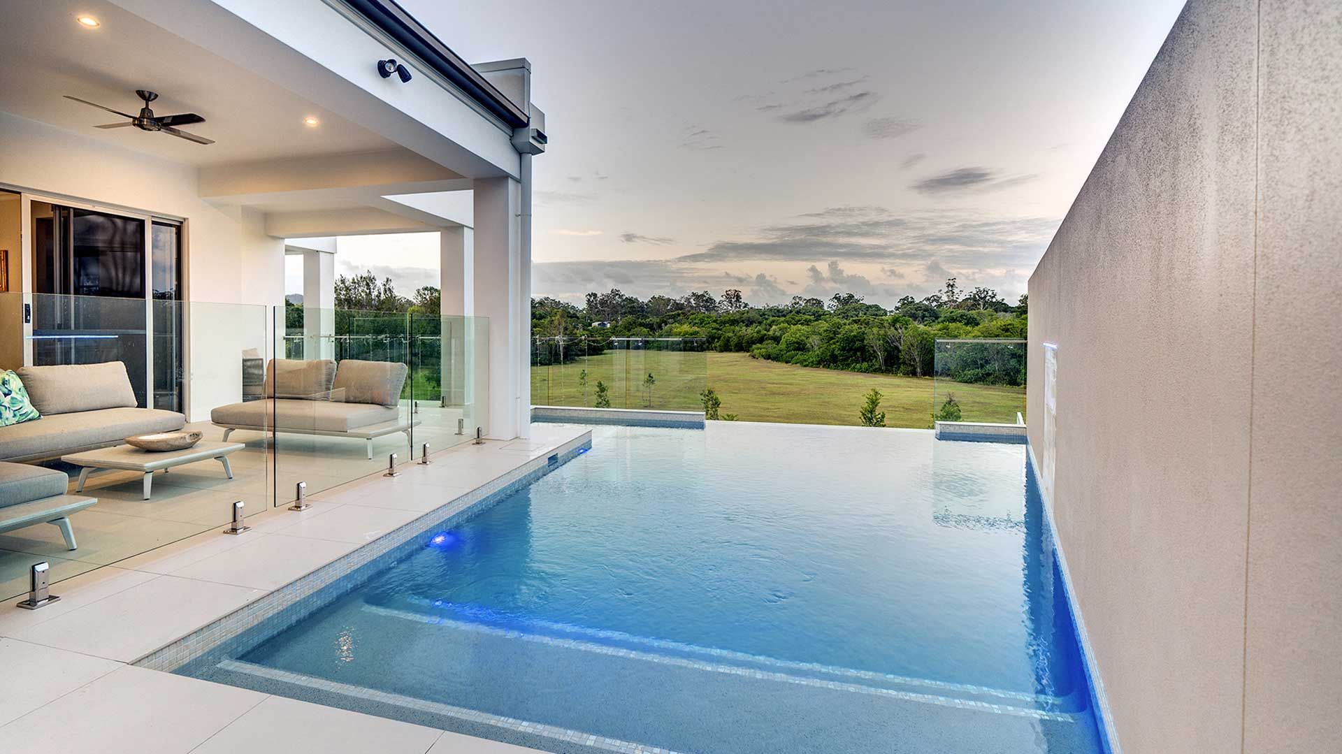 Modern white house with a swimming pool reflecting the clear blue sky.