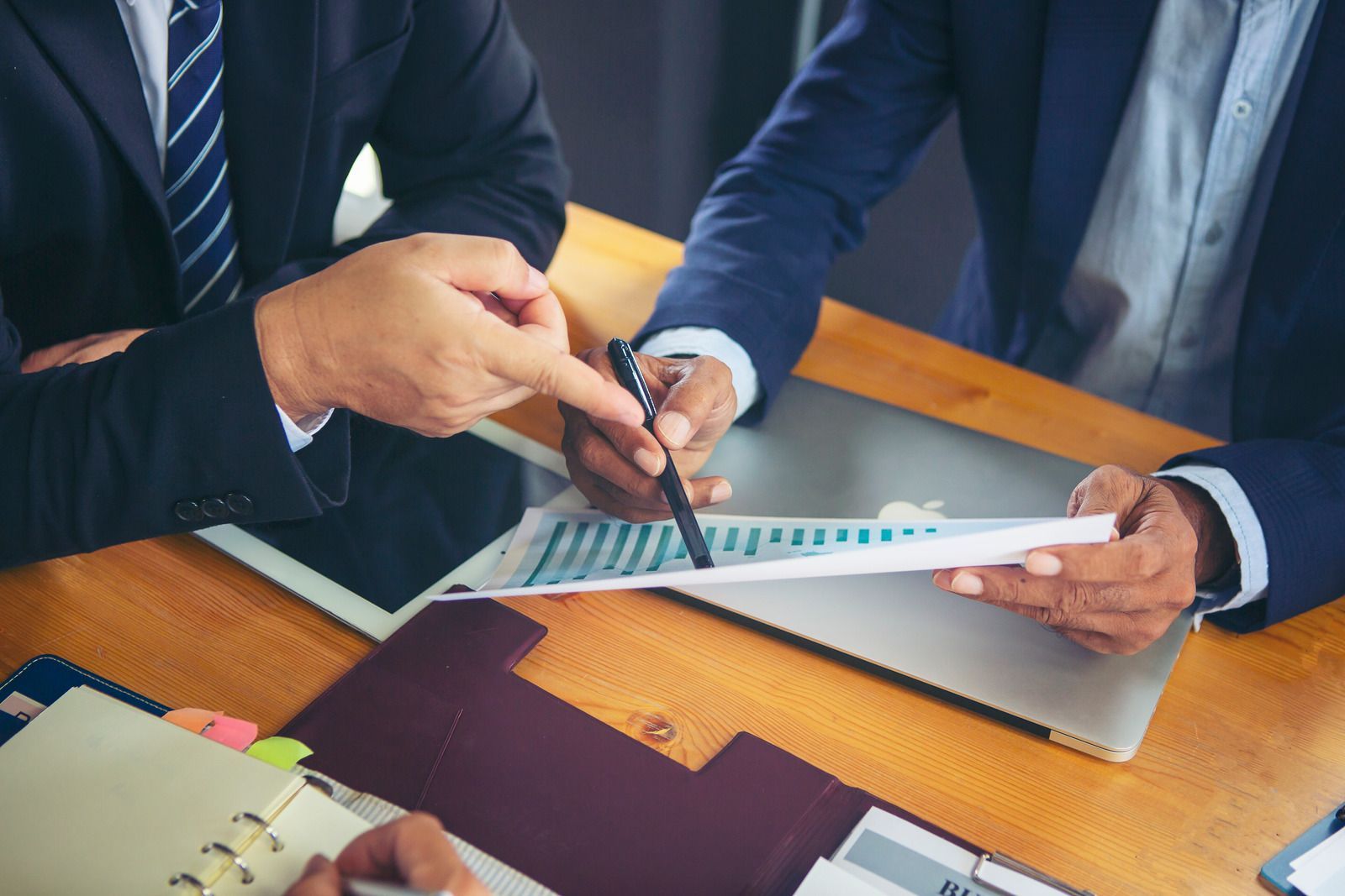 Two businessmen are sitting at a table looking at a piece of paper.