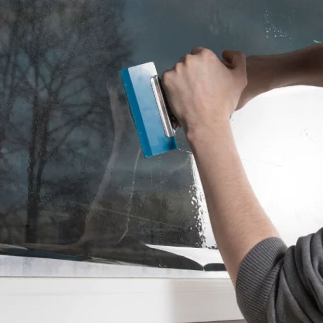 A person is cleaning a window with a squeegee