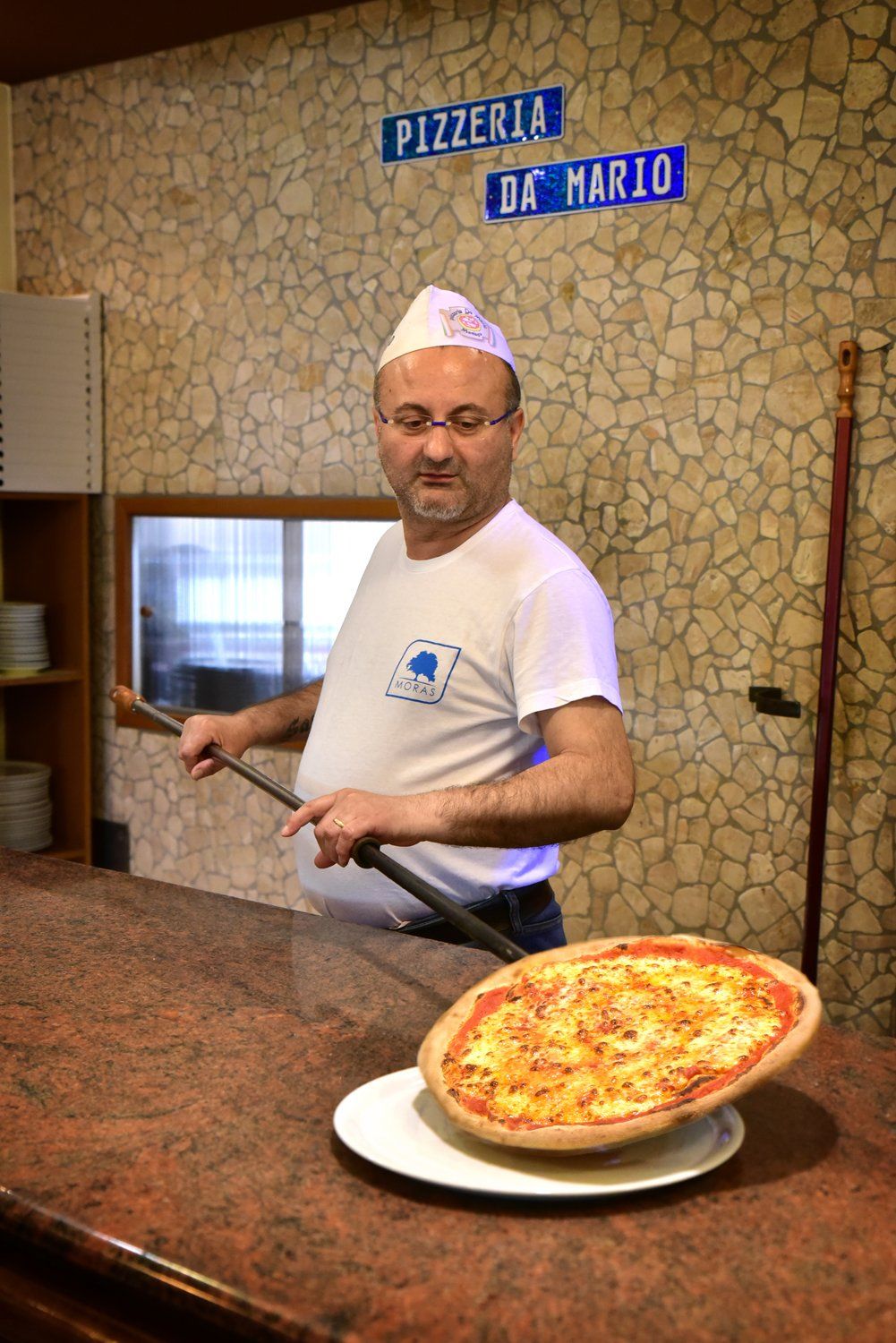 Il titolare mentre impianta una pizza