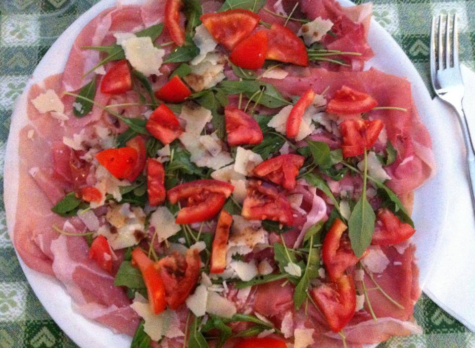 Pizza con mozzarella, rucola, scaglie di grana e pomodori