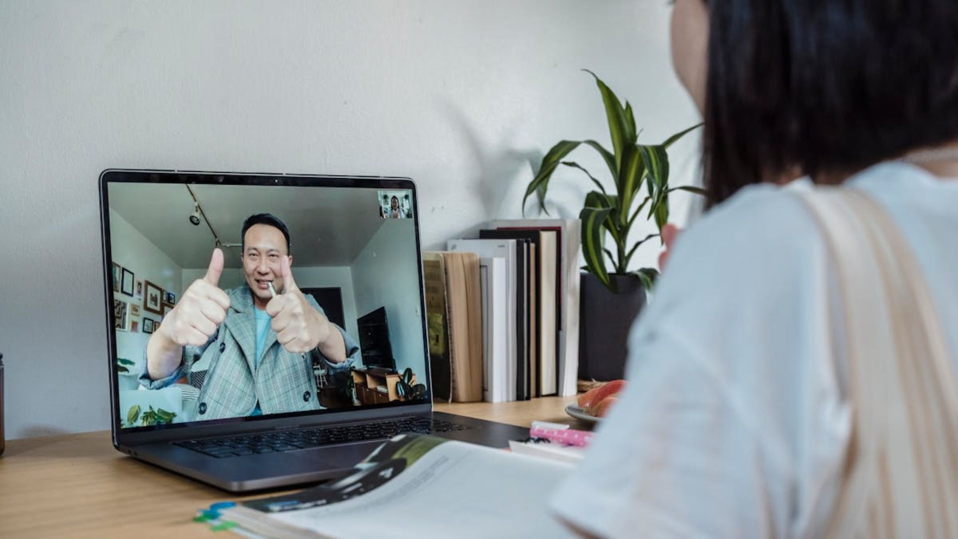 Una mujer está sentada en un escritorio usando una computadora portátil para tener una videollamada con un hombre.