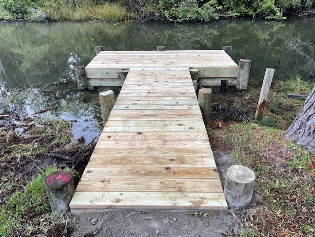 Wooden dock extending over water, with a small platform. Wooden posts support the structure. Wooden dock extending over water, with a small platform. Wooden posts support the structure.