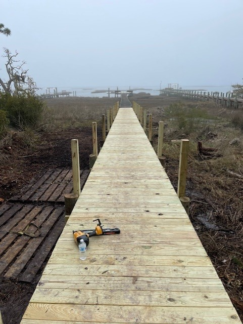 Wooden boardwalk leading to a foggy body of water. Tools and water bottle sit on the boards. Wooden boardwalk leading to a foggy body of water. Tools and water bottle sit on the boards.