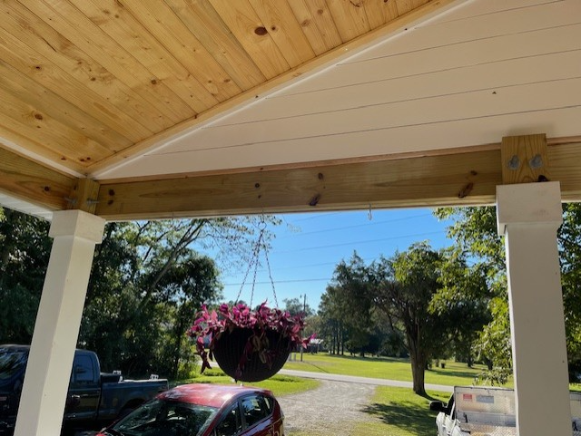 Roof partially covered with dark metal panels, exposed wooden frame against blue sky.
