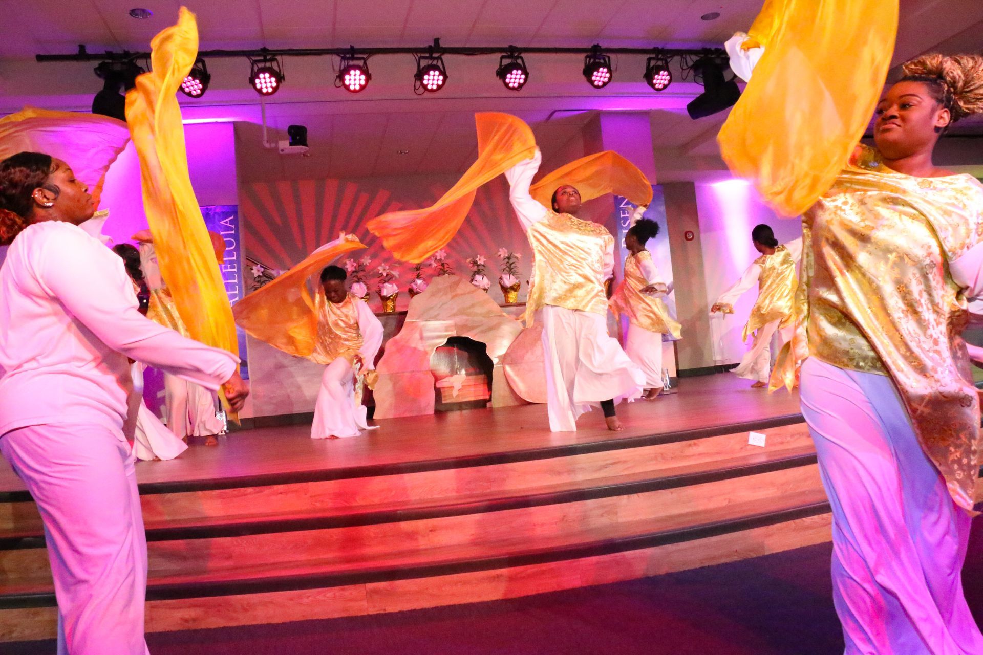 A group of women are dancing on a stage with flags in their hands