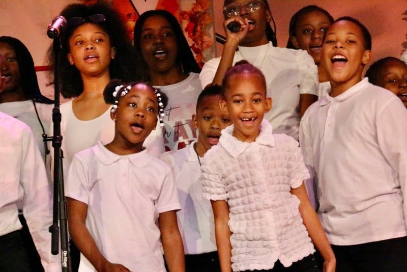 A group of children singing in front of a microphone