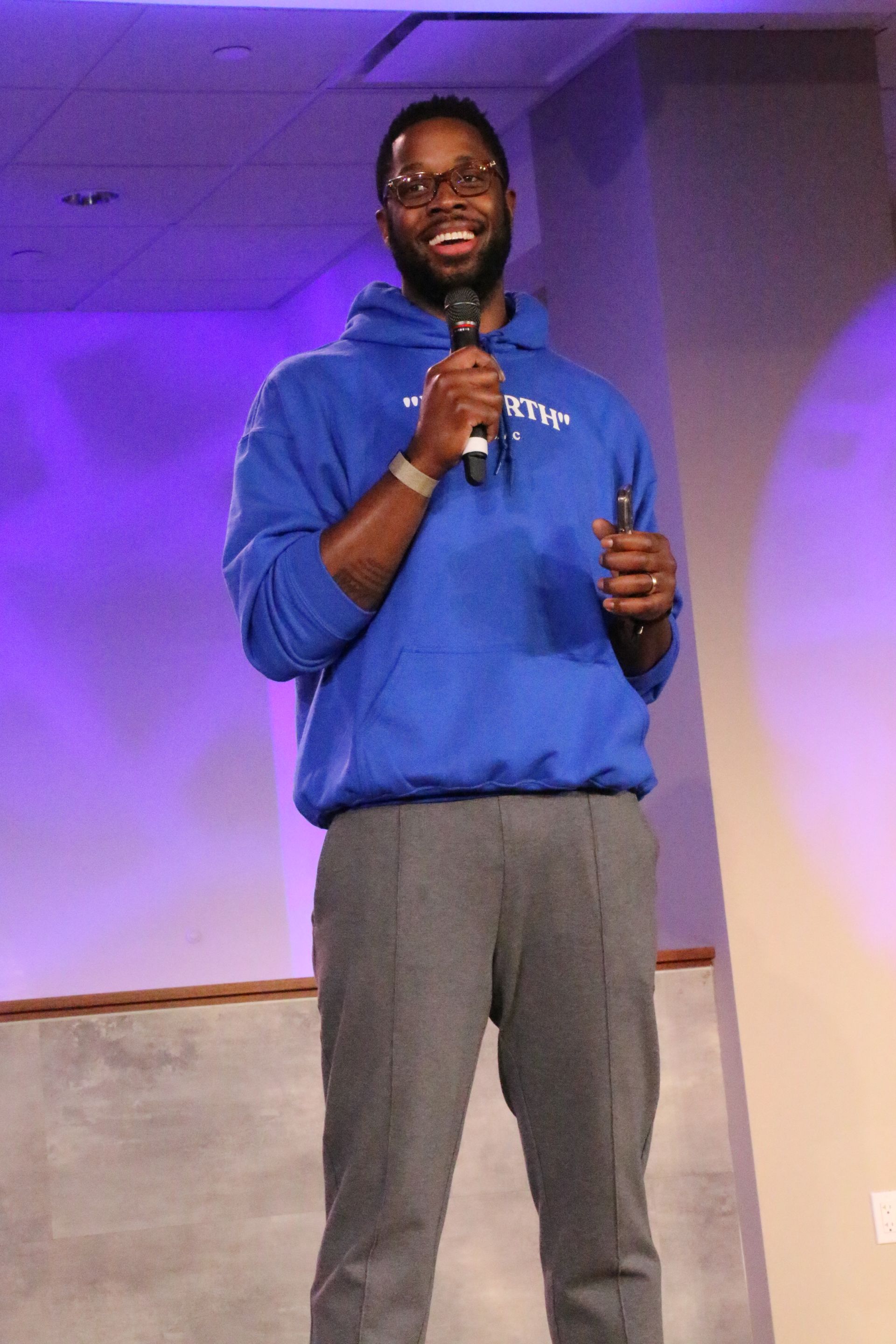 A man in a blue hoodie is holding a microphone
