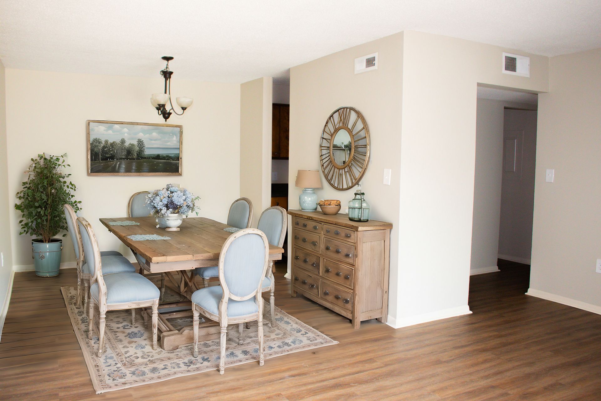 A dining room with a table and chairs and a clock on the wall.