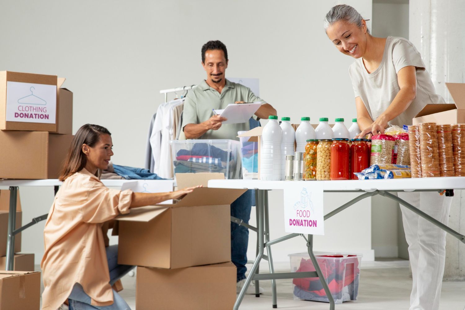 Volunteers sorting clothing and food donations into cardboard boxes at a donation center.