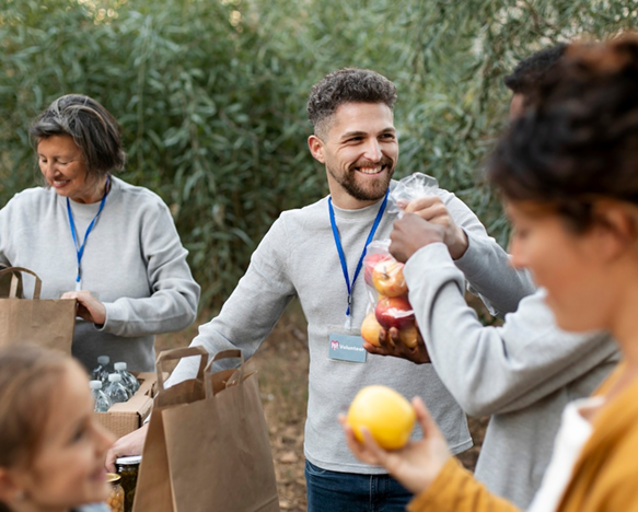 People in an outdoor setting packing and handing out bags of food as part of a community service event.