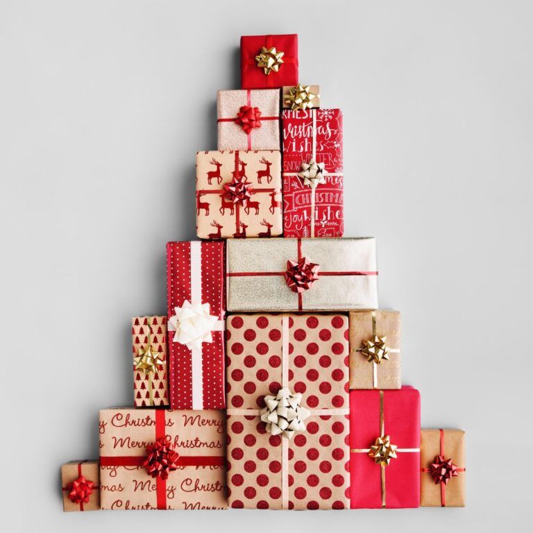 A Christmas tree shape made of stacked wrapped gift boxes in various patterns and colors against a grey background.