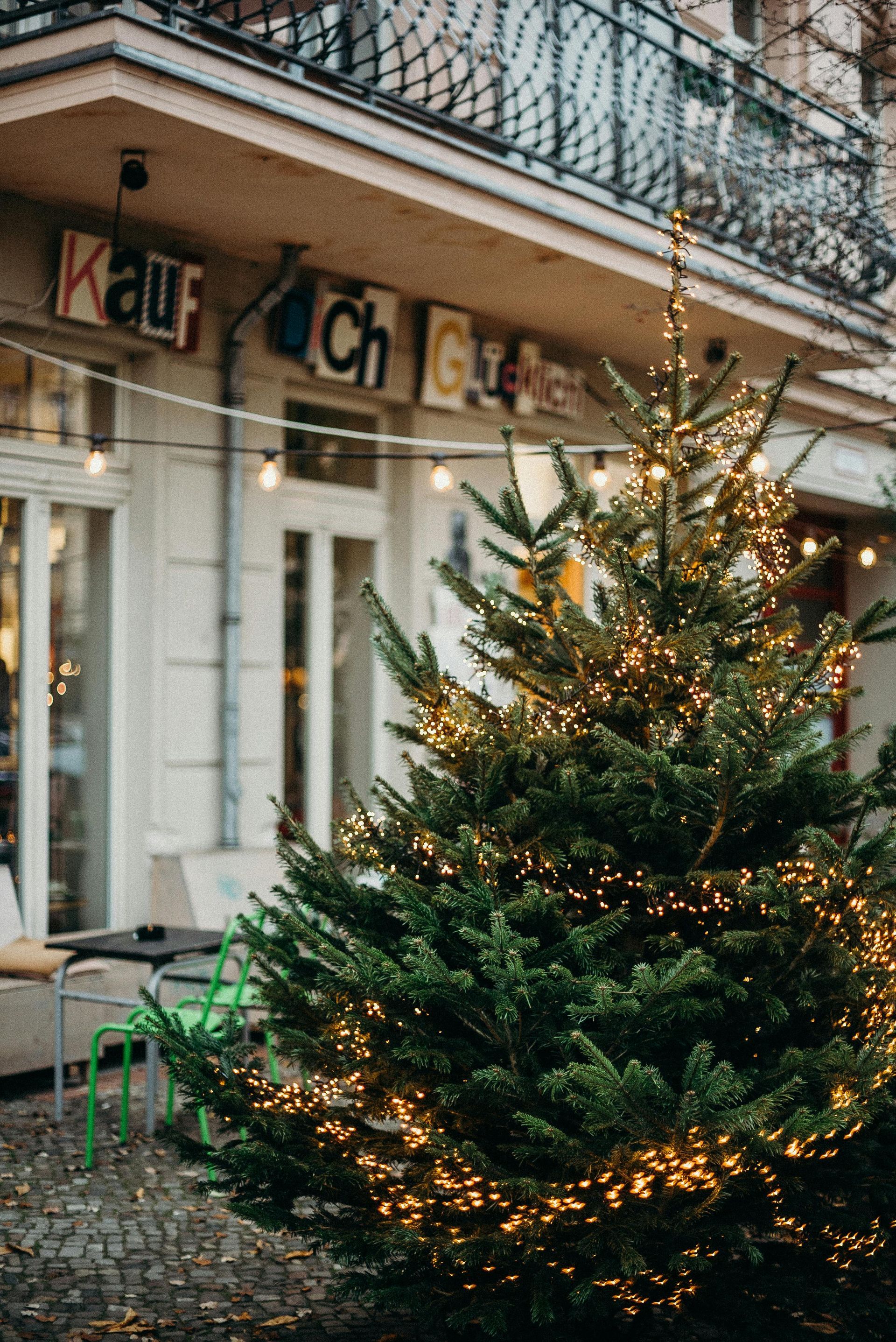 A christmas tree is lit up in front of a building.