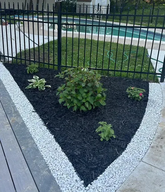 A garden with a fence and a pool in the background
