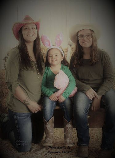 Three people sitting together, wearing cowboy hats and bunny ears, posing for a photo outdoors.
