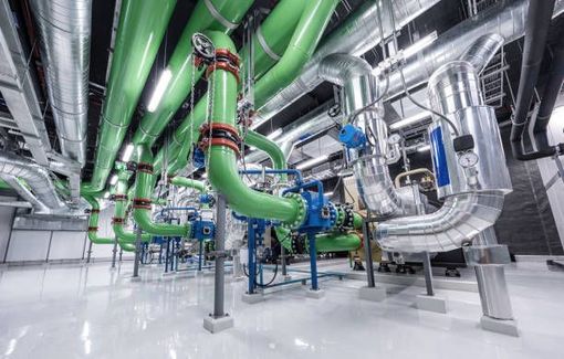 A bunch of green pipes are hanging from the ceiling of a building.