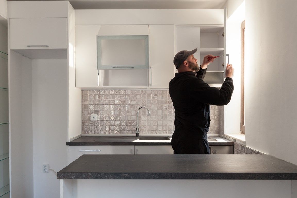 Carpenter installing white custom kitchen cabinets