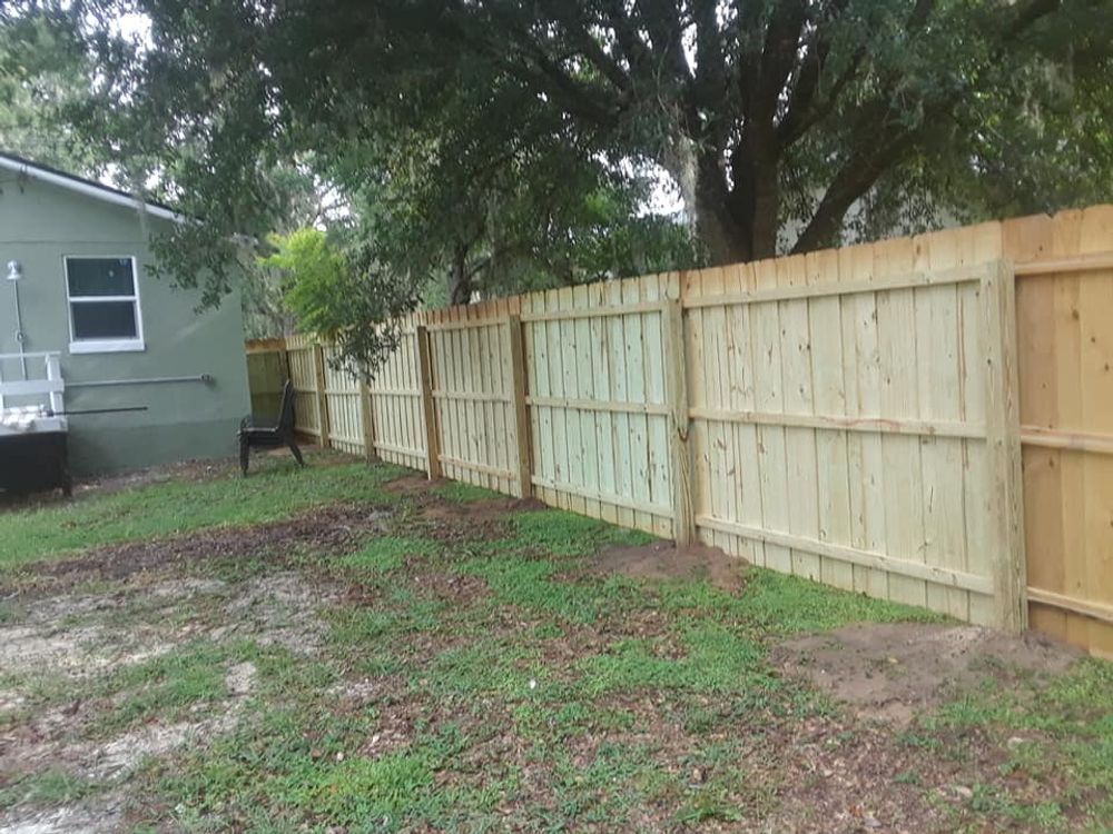 A wooden fence is in the backyard of a house.