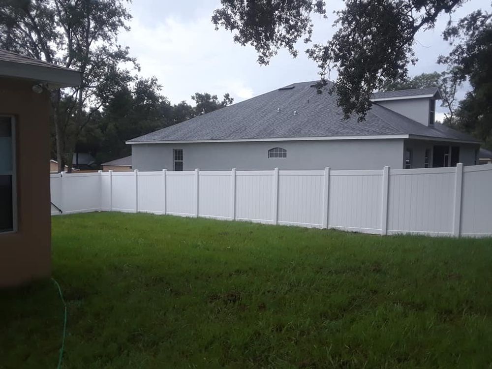 There is a white fence in the backyard of a house.
