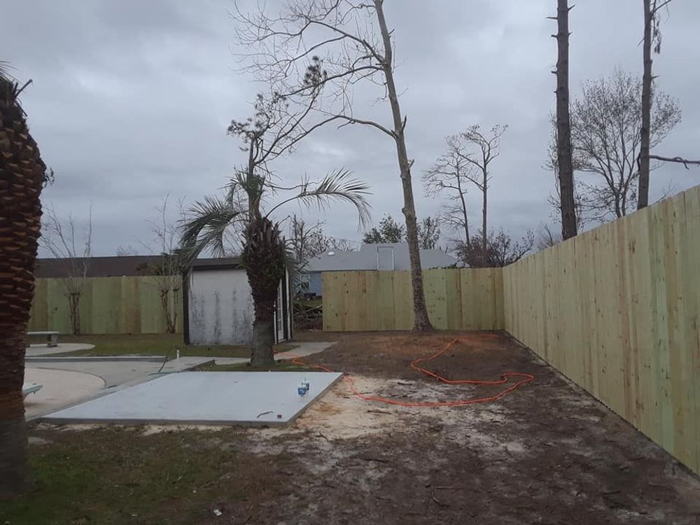 A wooden fence surrounds a swimming pool in a backyard.