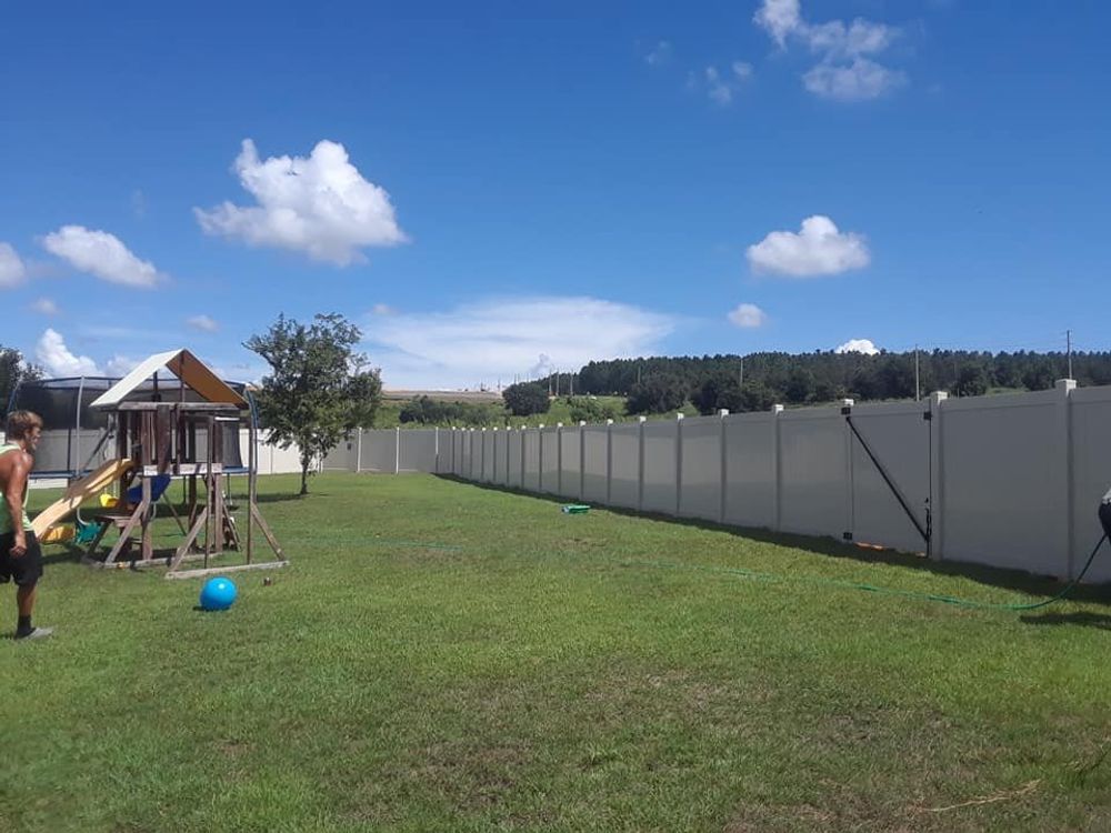 A white fence surrounds a playground in a backyard